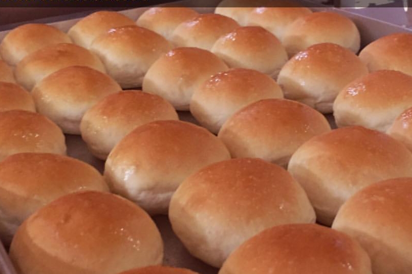 Pães de batata frescos e macios com superfície dourada em tábua de madeira